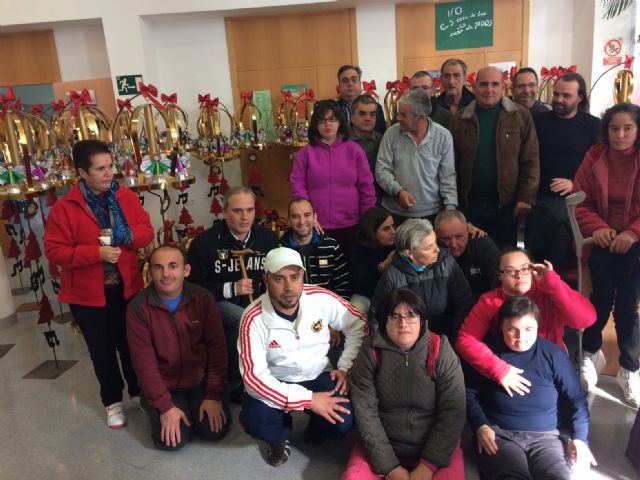 Usuarios de los centros de día para la discapacidad de Totana hacen entrega a la Asociación de Comerciantes de los adornos de Navidad que decorarán de forma uniforme los establecimientos adheridos a esta entidad